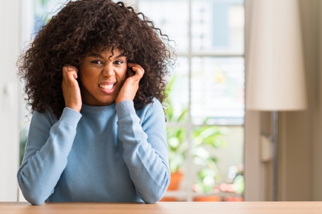 image of homeowner covering ears due to loud hvac ductwork noises