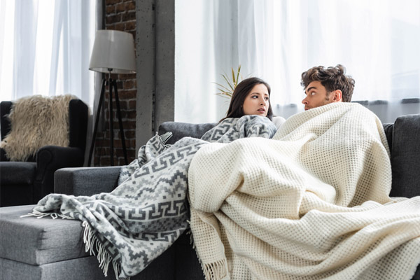 image of a couple feeling chilly at home due to a malfuntioning boiler