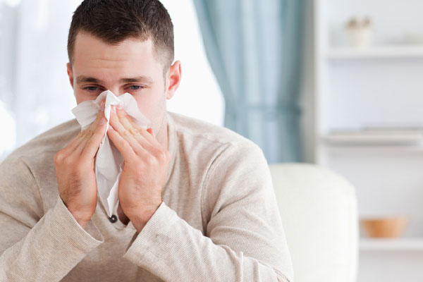 man sneezing due to poor indoor air quality and neglecting hvac air filter replacements