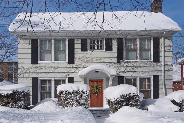 two story house covered in snow depicting uneven heating in house
