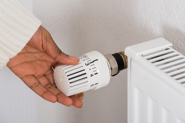 homeowner adjusting radiator temperature of oil boiler