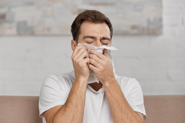 man sneezing due to poor indoor air quality