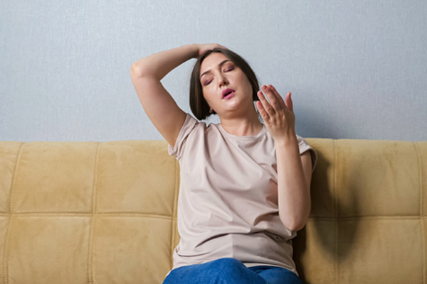 woman suffering from heat at home depicting heat pump blowing hot air in cool mode