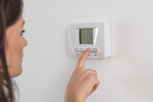 image of homeowner adjusting thermostat fan settings