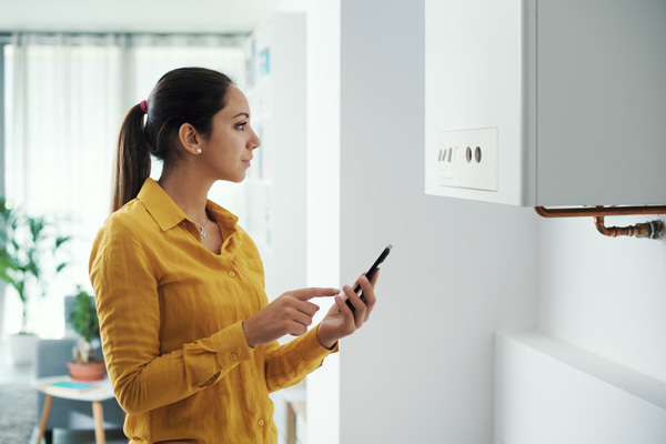 image of a woman managing and programming her smart thermostat and oil boiler